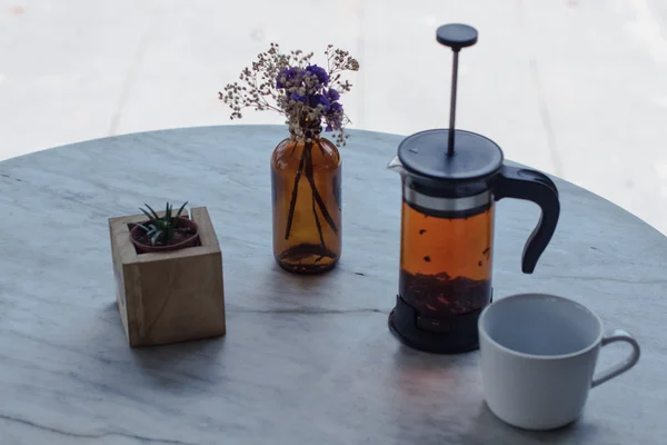 Chá quente uma prensa, uma caneca branca em uma mesa branca e um vaso com uma flor — Fotografia de Stock