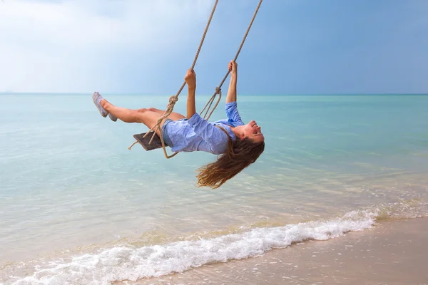 Plajda salıncakta sallanan genç bir kadının moda tarzının yaz portresi seyahat gereksinimlerine karşı, gülümsemesi izin günlerini ele geçirir. — Stok fotoğraf