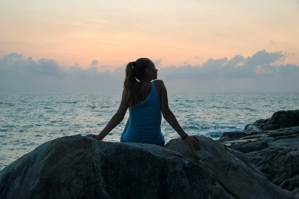 The beautiful girl sitting on stones and looking in a distance, the girl at sunset to meditate in silence, beautiful telo.concept .Siluet lonely girl sitting on the precipice of a cliff at sunset. — Stock Photo, Image