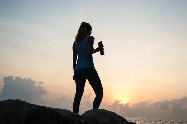 Güzel kız taşlar üzerinde oturan ve bir mesafeden bakarak, sessizlik içinde meditasyon gün batımında kız, güzel telo.concept . Gün batımında bir uçurumun kenarında oturan siluet yalnız kız. — Stok fotoğraf