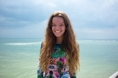 Kabarık esmer uzun saçları ile çekici güzelliği kapatın, beyaz bir duvarda neşeyle vakit geçiren gülümseme, elbise bir elbise, tatil tarzı, sonbahar görünümü, kuaför,