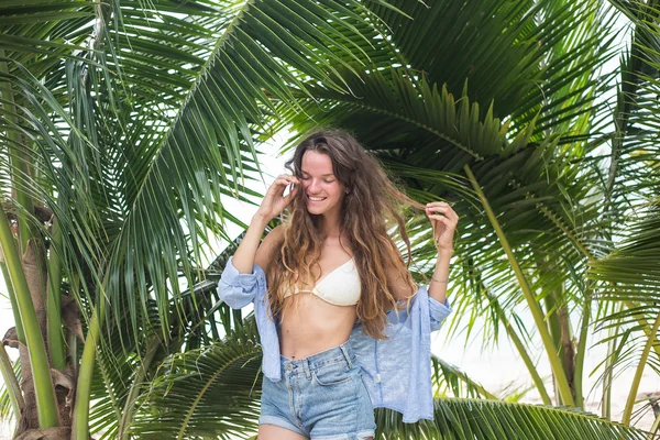 Het gelukkige meisje, wordt in de tropen, zit alot van gras, bomen, zeeën, warme foto, meisje het wezen op de zee, modieuze zhknshchina, een glimlach op het gezicht — Stockfoto