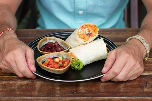 Burrito on ceramic ware, the Man eats a burrito, tasty, it is useful, vegetarian food