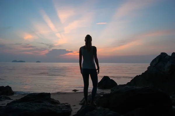 La ragazza al tramonto in piedi sulla riva del mare, il cielo colorato — Foto Stock