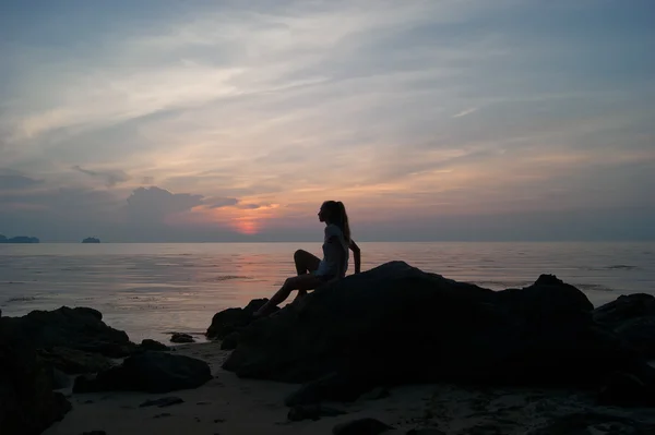 La ragazza al tramonto in piedi sulla riva del mare, il cielo colorato — Foto Stock