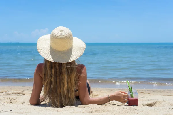 La foto de la señora hermosa sana en el sombrero blanco y la imposición negra del bikini sobre la arena, el paisaje asombroso del mar, se enfría, el verano desarrollan a la mujer, el jugo de sandía, el estilo rosado —  Fotos de Stock