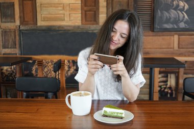 Kafe, fotoğraf üzerinde telefon yemek, çay, kahve, pasta yeşil bir fincan genç kız