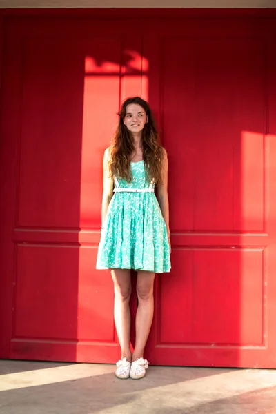Dziewczyna na czerwonym tle w zielonej sukience — Zdjęcie stockowe