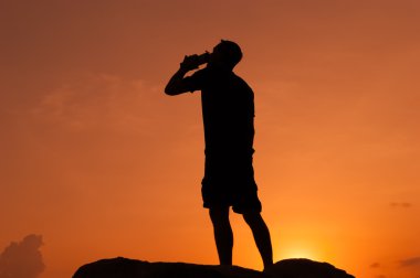 Adam bir şişeden şafak vaktinde içiyor.