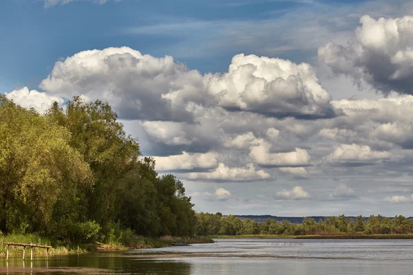 Пейзаж з хмарами над водою та лісом — стокове фото