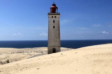 Landscape photo with a view of the North Sea coast against a blue sky with clouds near Hirtshals Fyr Lighthouse in Denmark