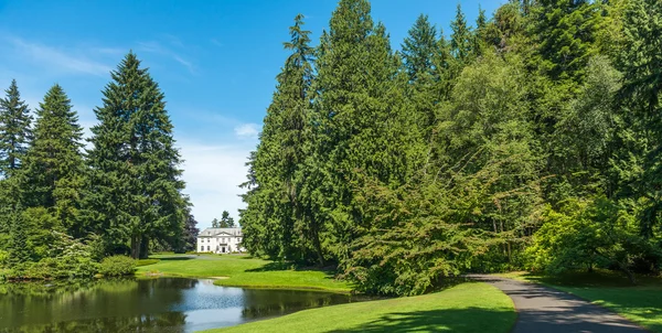 scenic view of lawn and trees with reflection in the lagoon in botanical garden..