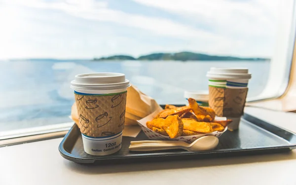 foods and coffee in cafeteria near by big window with view of the island in the back ground,in ferry..