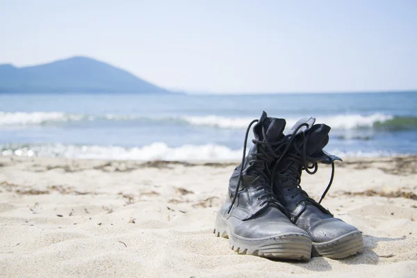 Alte Stiefel ruhen am Strand. — Stockfoto