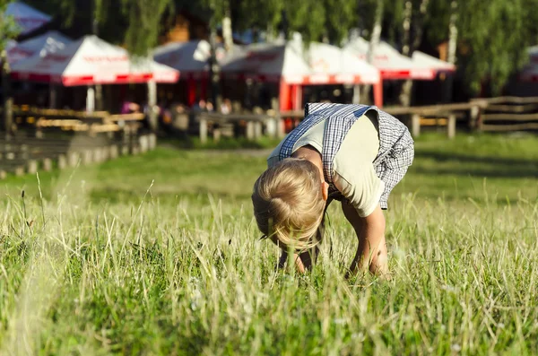 Bonito menino loiro brincando em um parque gramado — Fotografia de Stock