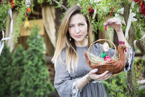 Young beautiful girl with a basket with Easter eggs on background Easter tree — Stock Photo, Image