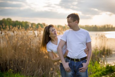 Gülümseyen göl kıyısında günbatımı ayakta Çift