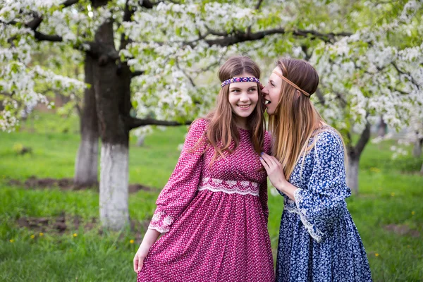 Two pretty women in long dresses - mother and daughter are walking in the lush spring garden — Stock Photo, Image