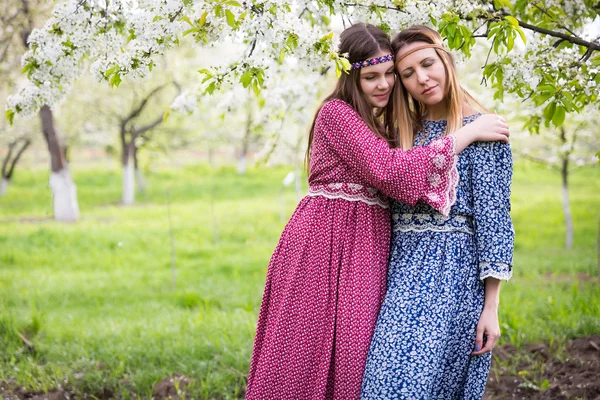 긴 드레스-어머니와 딸에에서 두 예쁜 여자 무성 한 봄 정원에서 걷고 있다 — 스톡 사진