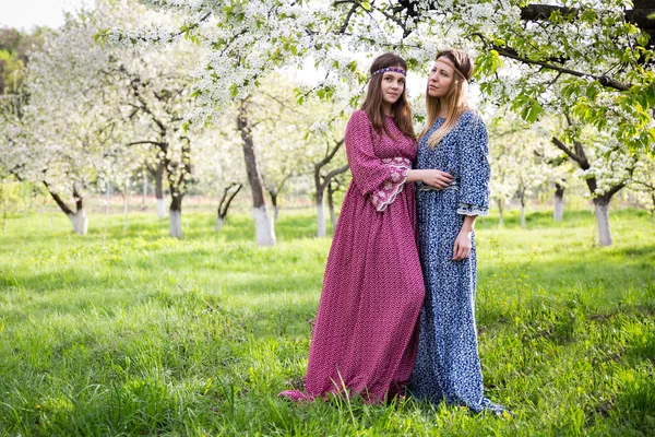 긴 드레스-어머니와 딸에에서 두 예쁜 여자 무성 한 봄 정원에서 걷고 있다 — 스톡 사진
