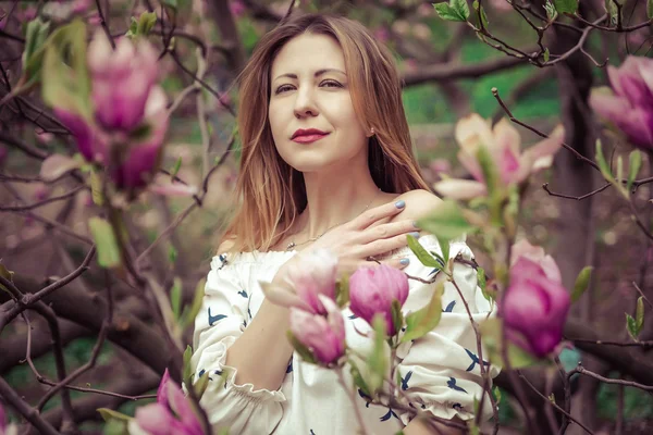 Jeune belle femme caucasienne en fleurs jardin printanier de magnolias. La fille dans le jardin par une journée nuageuse  . — Photo
