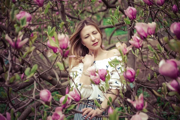 Jeune belle femme caucasienne en fleurs jardin printanier de magnolias. La fille dans le jardin par une journée nuageuse  . — Photo