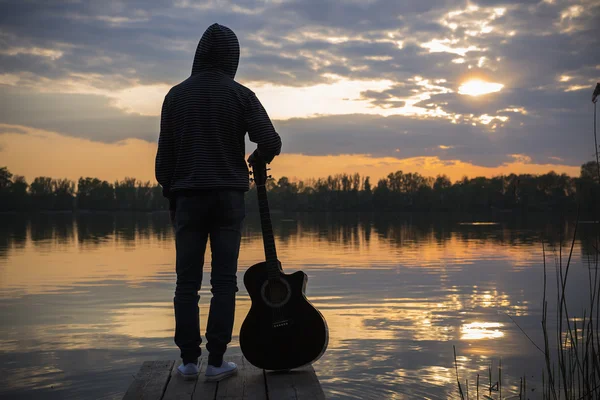 Homem de pé com guitarra ao pôr-do-sol — Fotografia de Stock