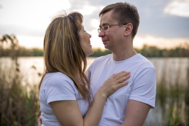 Gün batımında göl kıyısında çift ayakta