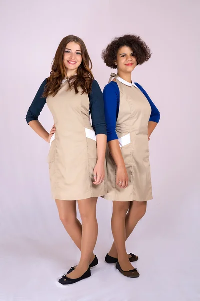 Δύο ωραία κοπέλα από διαφορετικές εθνικότητες Καυκάσιος και Λατίνα που θέτουν σε στούντιο στο ποδιές. βιομηχανία ομορφιάς — Φωτογραφία Αρχείου