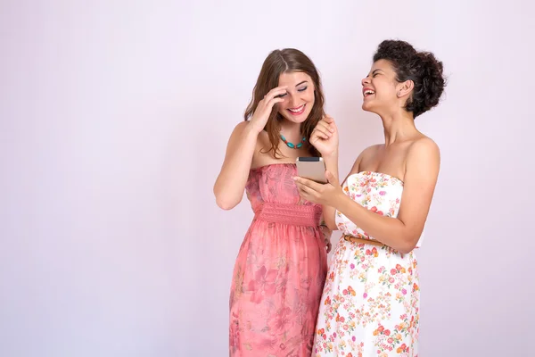 Két barátnő nevetve egy okostelefon a kezében. Technológia, Internet, kommunikáció — Stock Fotó
