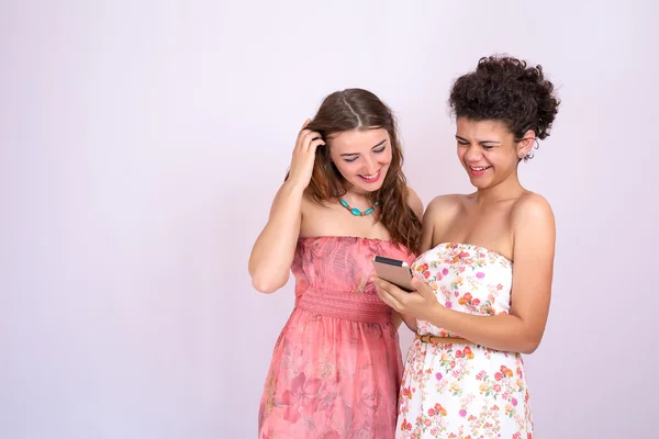 Két lány különböző fajú kölcsönhatásba lépnek, és megvitassák az információk a smartphone. Internet, kommunikáció — Stock Fotó