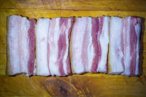 Appetizing pieces of bacon with a slot on the background of a wooden surface — Stock Photo, Image