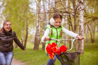 mutlu anne kızı Bisiklete binmeyi öğretir. Bir anne kızının başarıları için sevindi