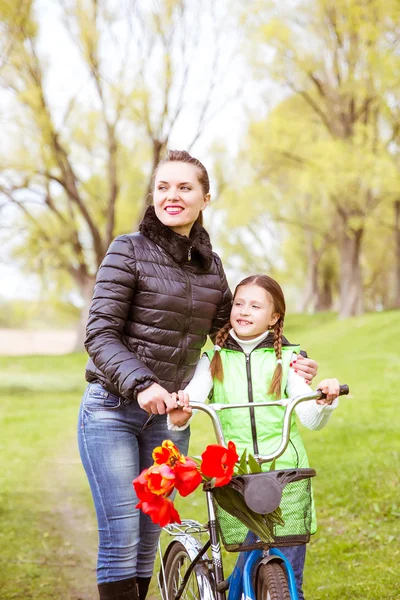 Dcera a matka chodí podél břehu jezera na kole a promluvit si. Rodinné hodnoty, vzdělání — Stock fotografie