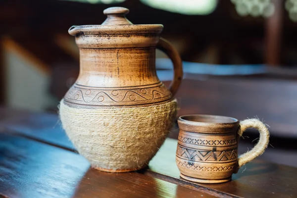 Pitcher and Cup of red clay with Ukrainian ornament on the wooden table — Stock Photo, Image