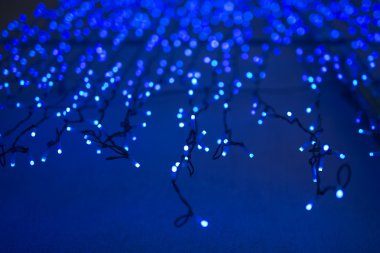 Koyu mavi arka planda fotokopi alanı olan Noel ışıkları. Dekoratif çelenk