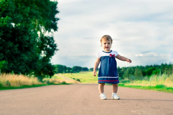 Kleines Mädchen im Kleid auf einer Landstraße — Stockfoto