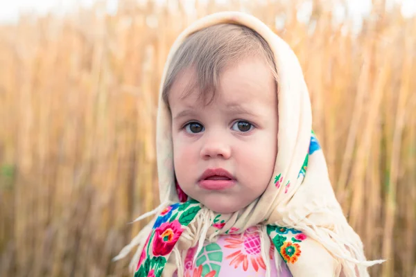 Bambina in sciarpa si trova in mezzo al campo . — Foto Stock