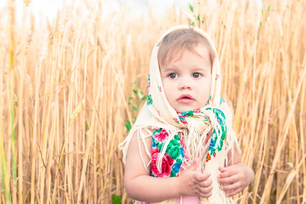 Kleines Mädchen mit Schal steht mitten auf dem Feld. — Stockfoto