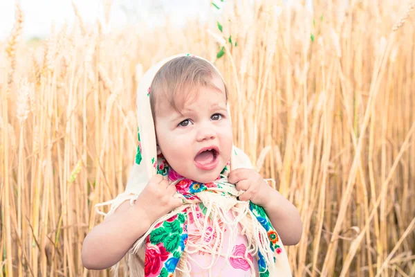 Das kleine Mädchen mit Schal steht mitten auf dem Feld und weint. Waisenkinder, soziale Probleme. — Stockfoto