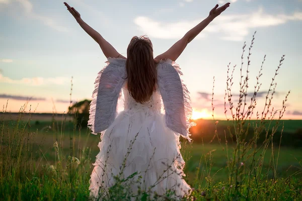 Uma jovem mulher à imagem do anjo está em uma colina com ra — Fotografia de Stock