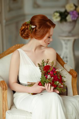 Very pretty sophisticated red-haired girl sitting in a chair wit