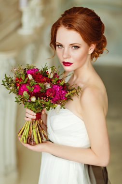 Very pretty sophisticated red-haired girl with a bouquet in hand