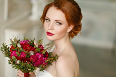 Very pretty sophisticated red-haired girl with a bouquet in hand