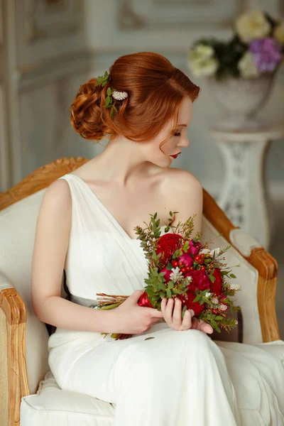 Very pretty sophisticated red-haired girl sitting in a chair wit — Stockfoto