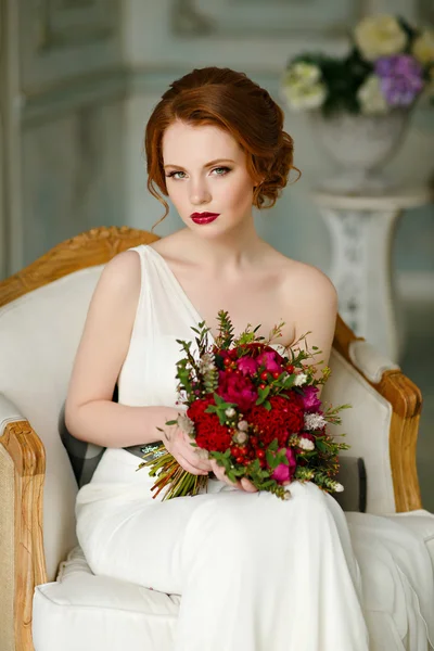 Very pretty sophisticated red-haired girl sitting in a chair wit