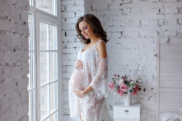 Beautiful soft and sensual pregnant girl in white transparent dr