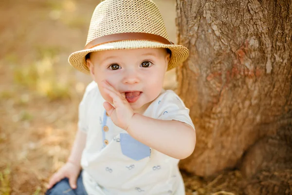 Niño pequeño con grandes ojos marrones y un sombrero chupa un dedo, en el — Foto de Stock