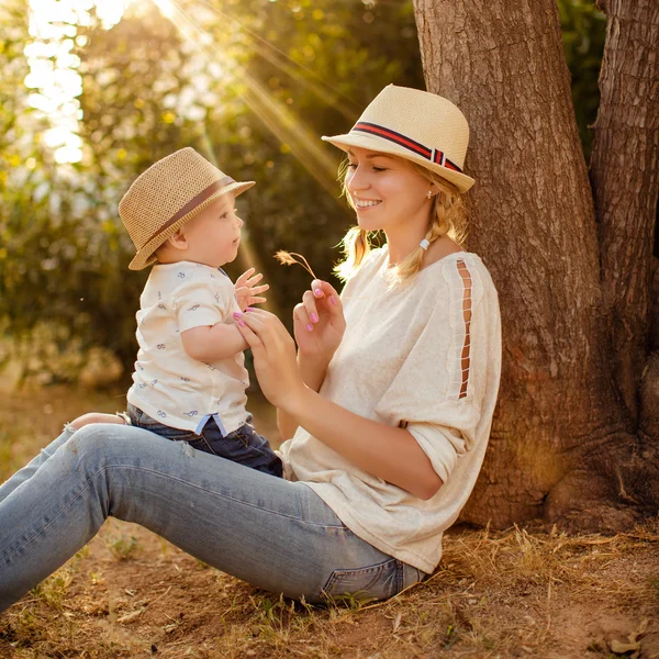 Delgada hermosa mamá rubia en jeans, una camisa beige y un sombrero h —  Fotos de Stock