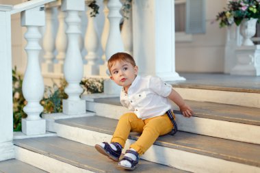 Çok şirin, şirin küçük çocuk sarı pantolon sta üzerinde oturur